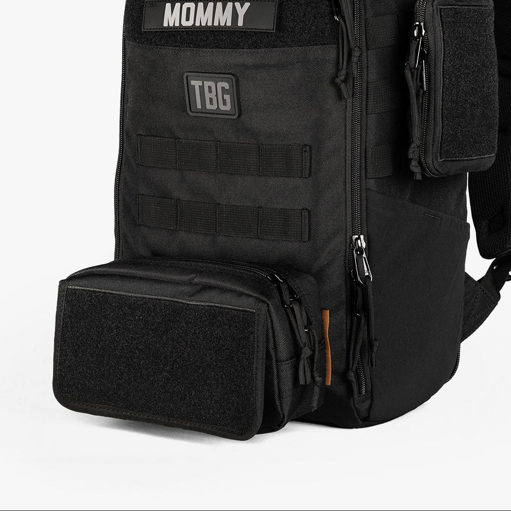 Rugged mini diaper bag with adjustable straps, featuring patches labeled "DADDY" and "MOMMY" and multiple storage compartments.