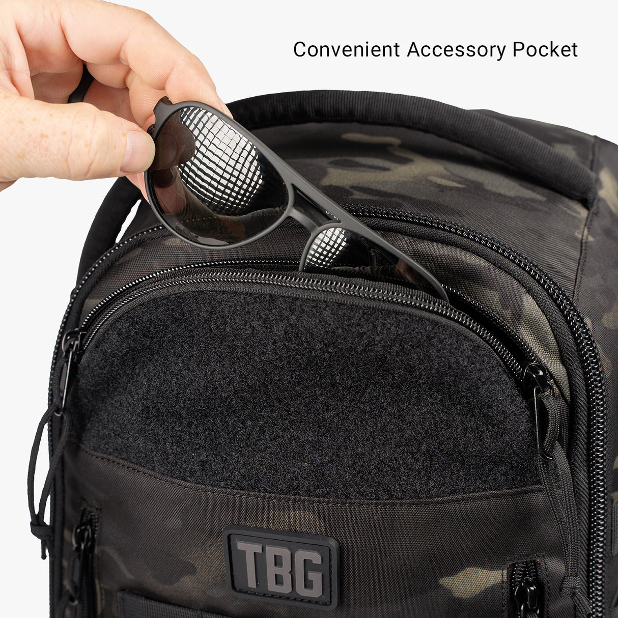 Black camouflage daypack diaper bag with baby carrier bundle, featuring a convenient accessory pocket and sunglasses inside.