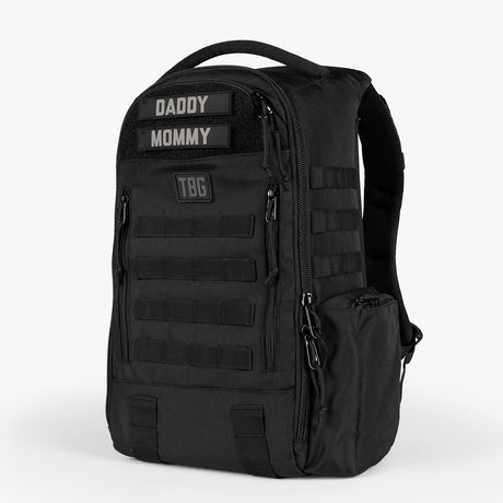 Black daypack diaper bag with multiple compartments, adjustable straps, and patches labeled Daddy and Mommy.