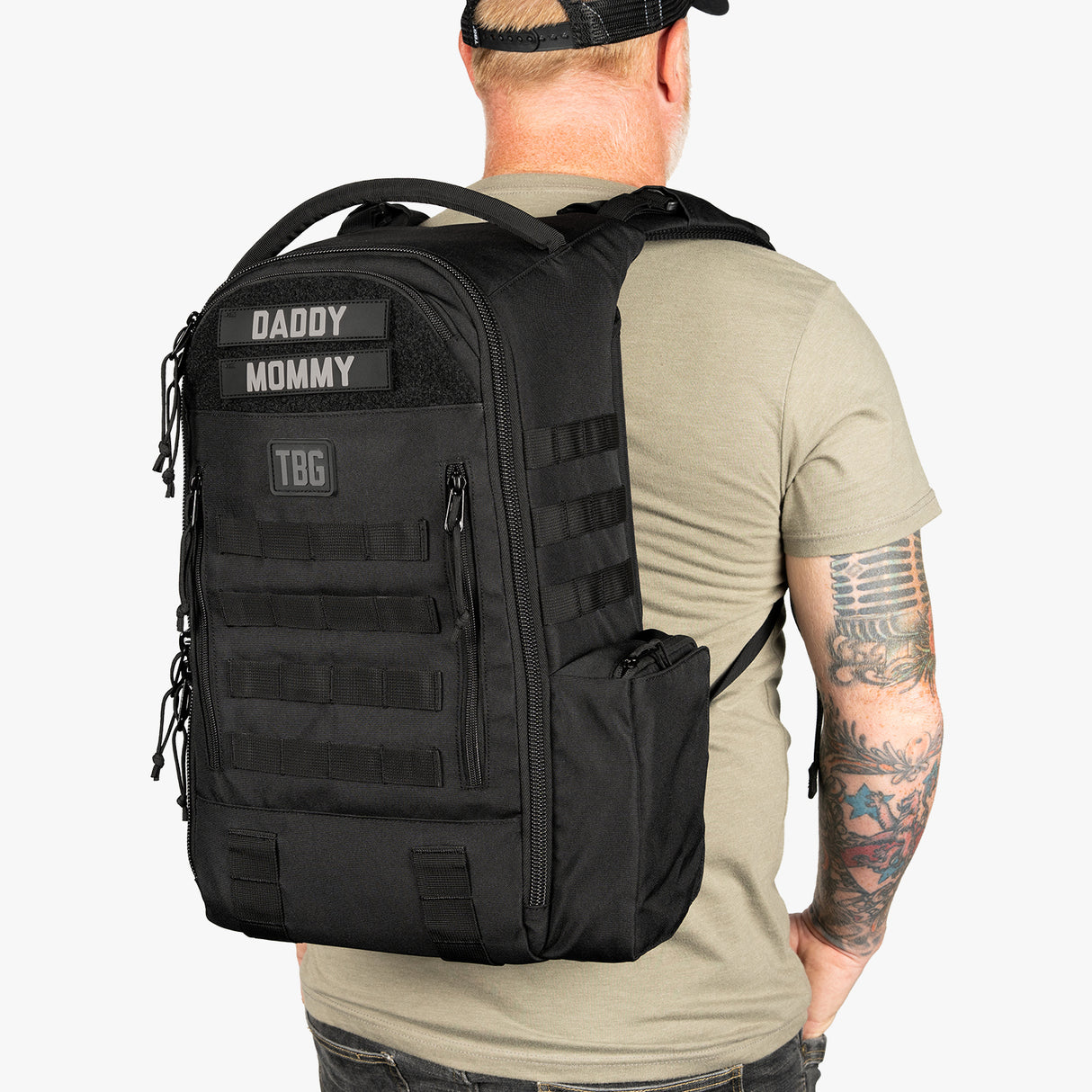 Black daypack diaper bag with baby carrier straps, labeled Daddy and Mommy, designed for parents on the go.