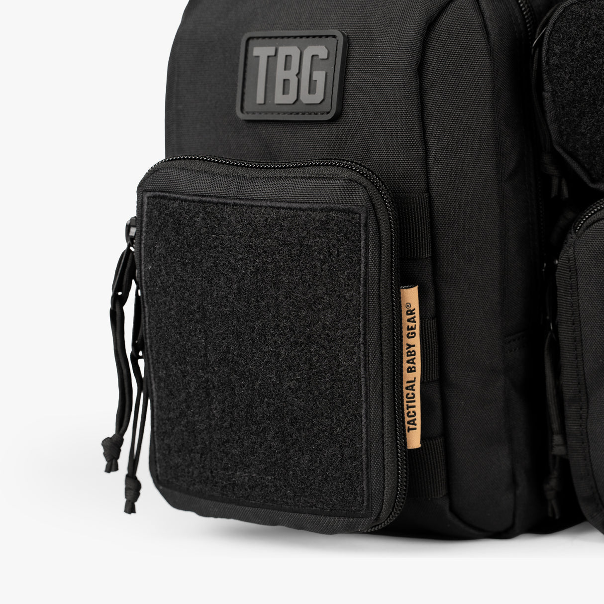 Close-up of a black diaper bag and baby carrier bundle with a large front pocket, tactical design, and Tactical Baby Gear label.