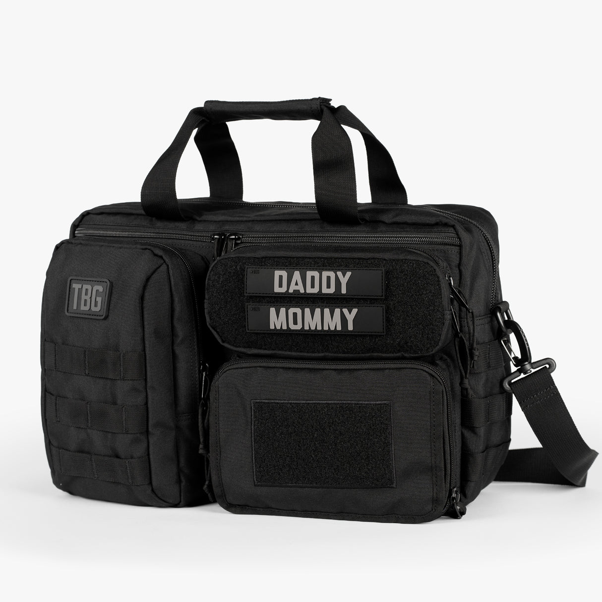 Black tactical diaper bag with multiple compartments, Velcro patches labeled Daddy and Mommy, and a detachable shoulder strap.