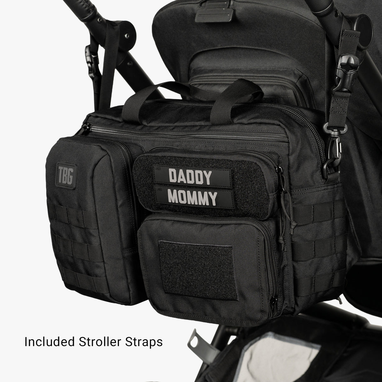 Black tactical diaper bag and baby carrier bundle attached to stroller, with labeled patches reading DADDY and MOMMY.