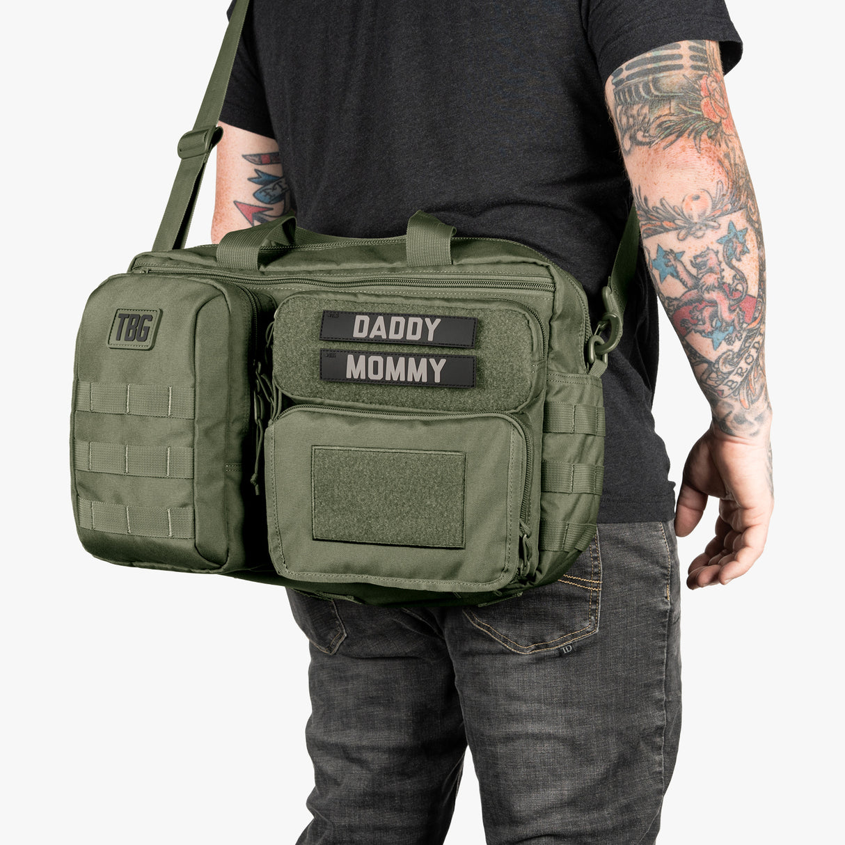 Green tactical diaper bag and baby carrier bundle with labeled patches for daddy and mommy, featuring multiple compartments.