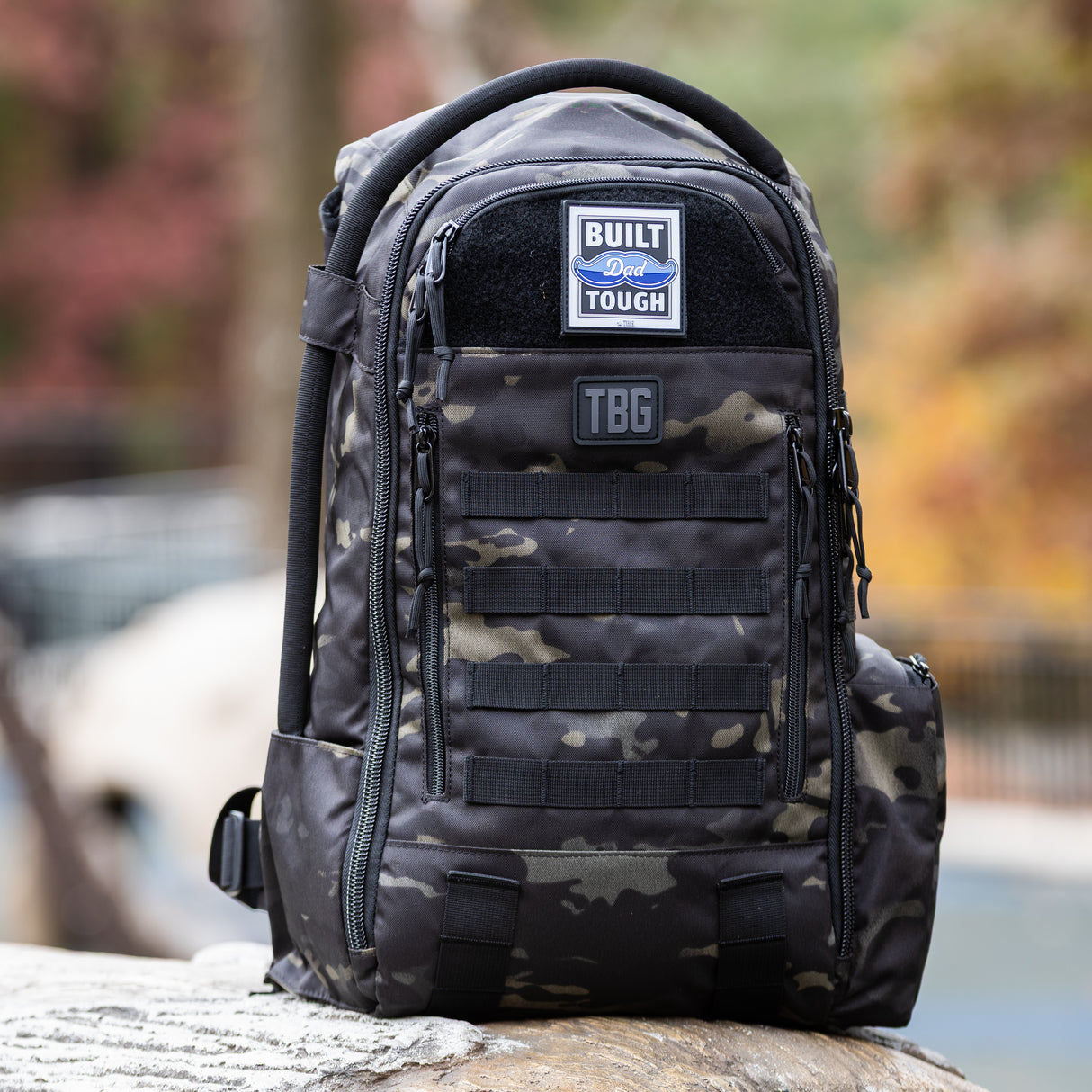 Tactical Baby Gear Built Dad Tough Patch on a rugged black camouflage backpack with multiple pockets and straps.