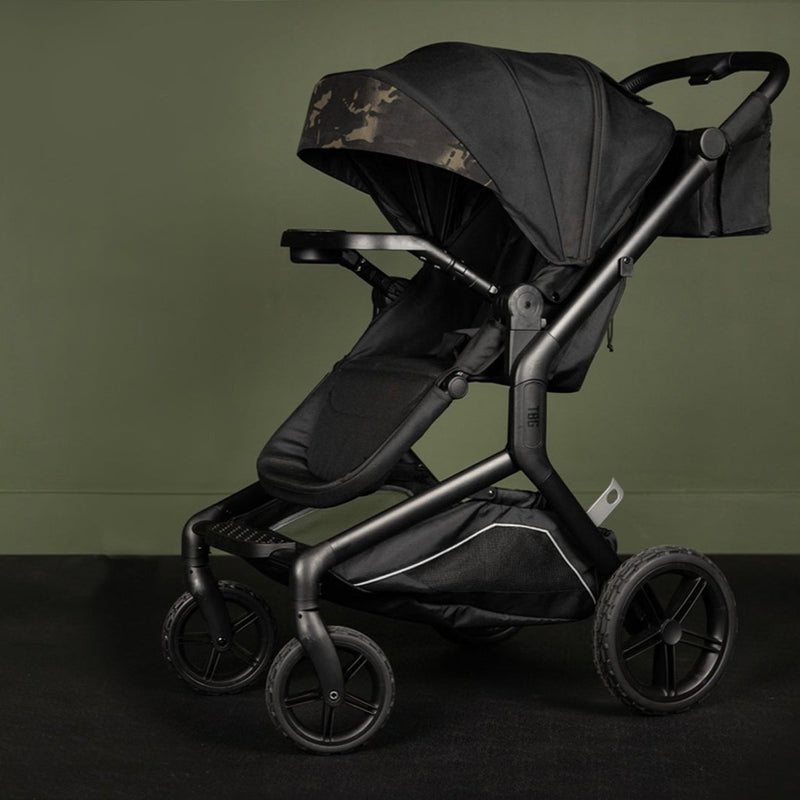 Black tactical-style stroller with a camouflage-patterned canopy, set against an olive-green background.
