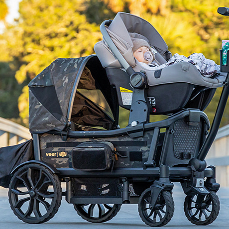 Rugged, military-style baby stroller in camouflage with large wheels and multiple compartments.