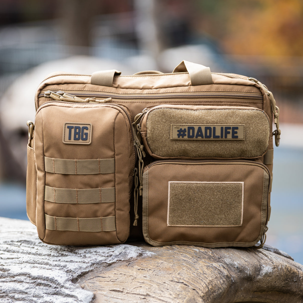 Tactical Baby Gear #DADLIFE Name Tape Patch on a rugged tan diaper bag with multiple compartments and patches.
