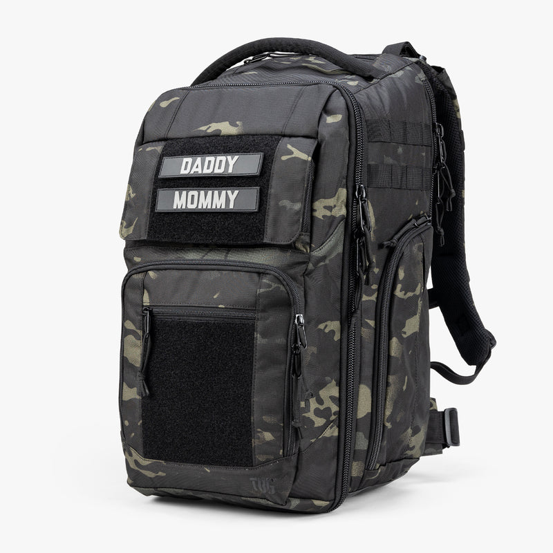 Rugged camouflage diaper bag with "Daddy" and "Mommy" patches, multiple zippered compartments, and padded shoulder straps.