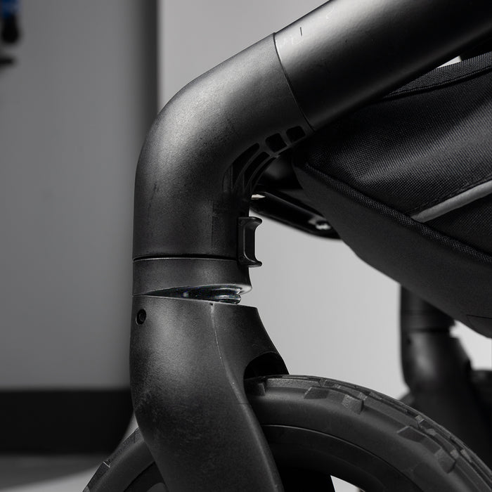 Close-up of a black, rugged stroller wheel and frame, highlighting durable construction.