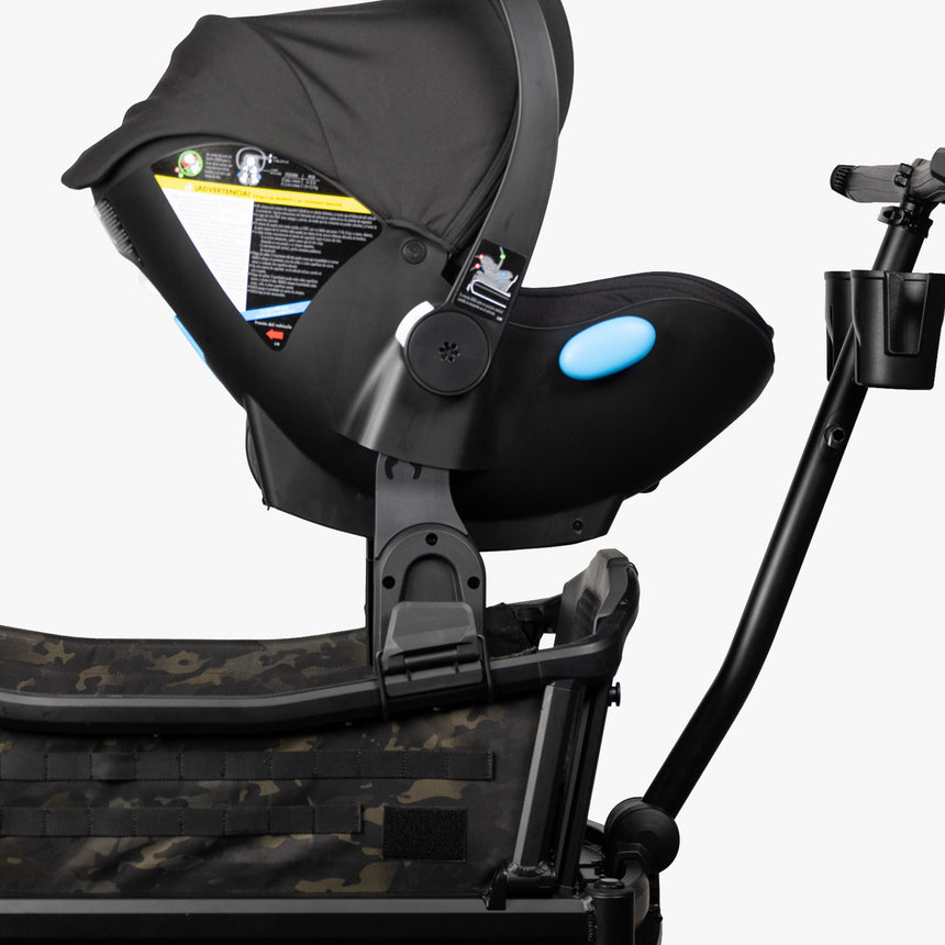 Alt text: "Clek car seat adapter attached to a stroller, featuring a camo-pattern stroller base, with the car seat equipped with a black canopy and blue handle details for secure attachment."