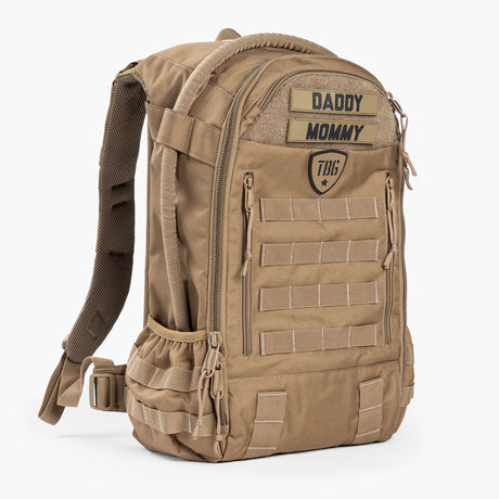 Tan military-style diaper backpack with "DADDY MOMMY" patch and multiple pockets.