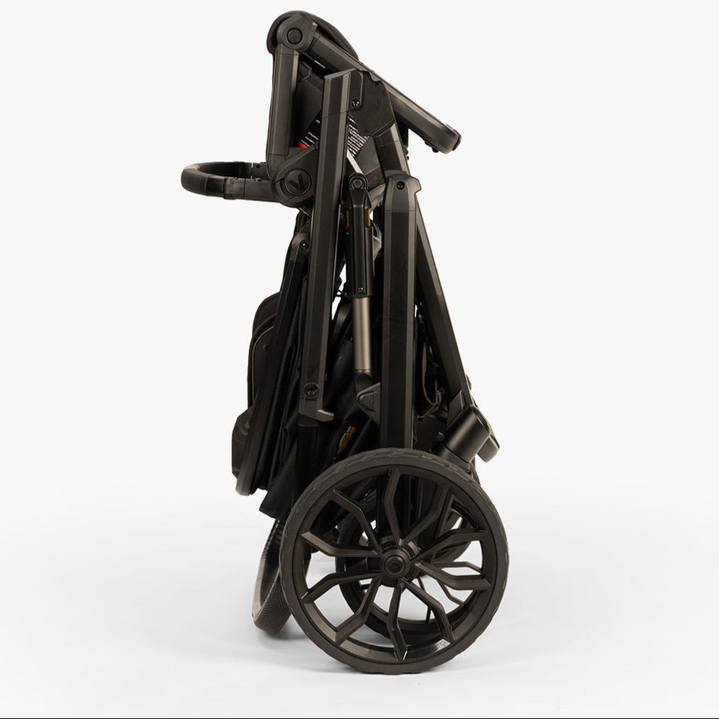 Compact, foldable baby stroller from TBG | Veer Switchback Newborn Bundle, shown from the side, in a neutral color.