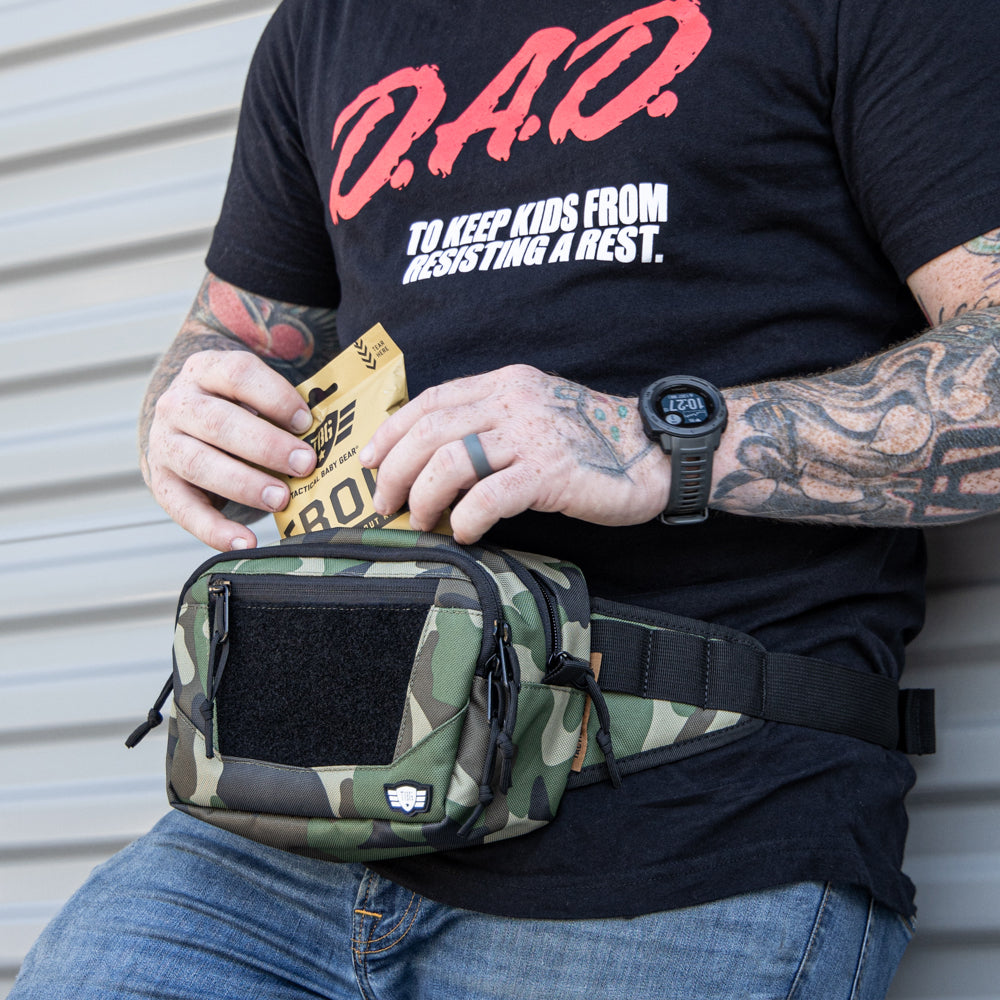 Man leaning up against a wall pulls an EBOK out of a fanny pack.