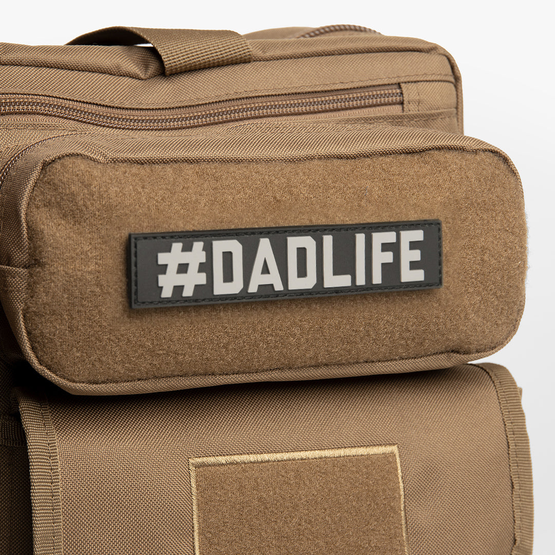 Black name tape patch with gray lettering reading #DADLIFE on brown bag.