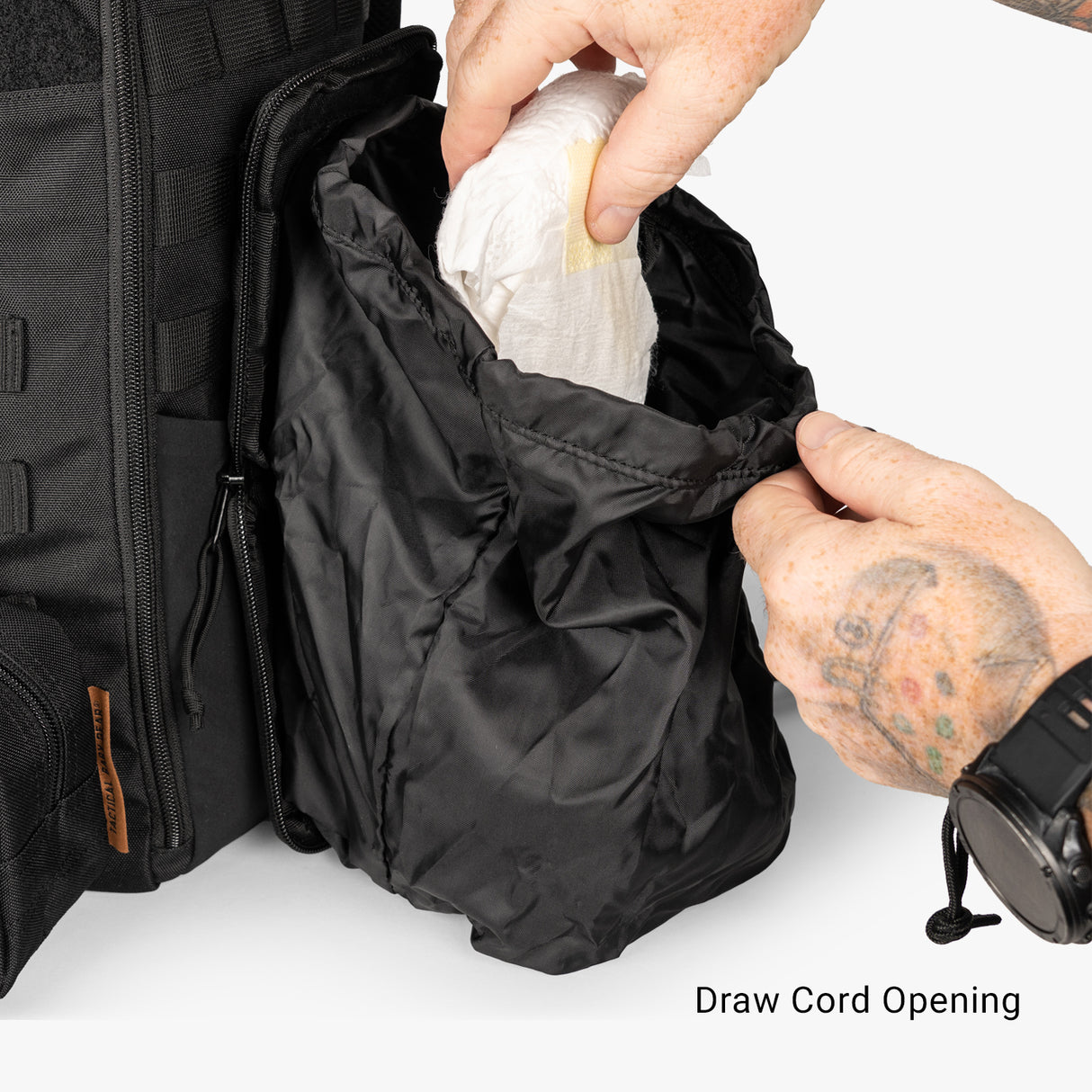 Hands pulling a diaper from a drawcord opening of a mini diaper bag, showcasing its practical design for parents.