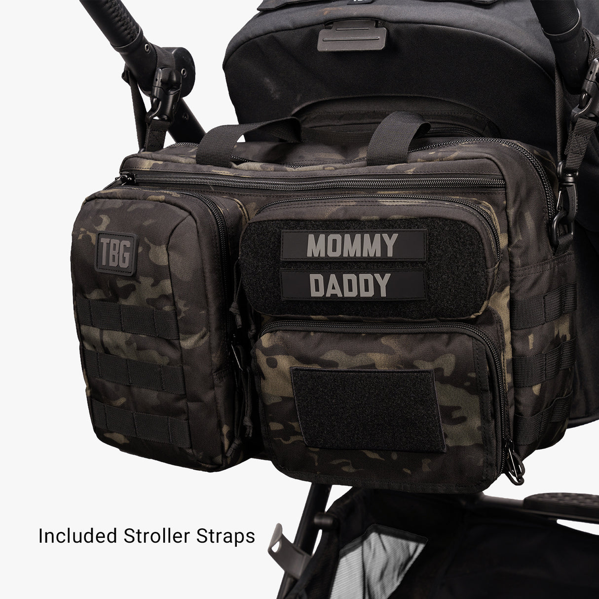 Rugged Deuce Diaper Bag with stroller straps, featuring customizable patches labeled "Mommy" and "Daddy" in a camo design.