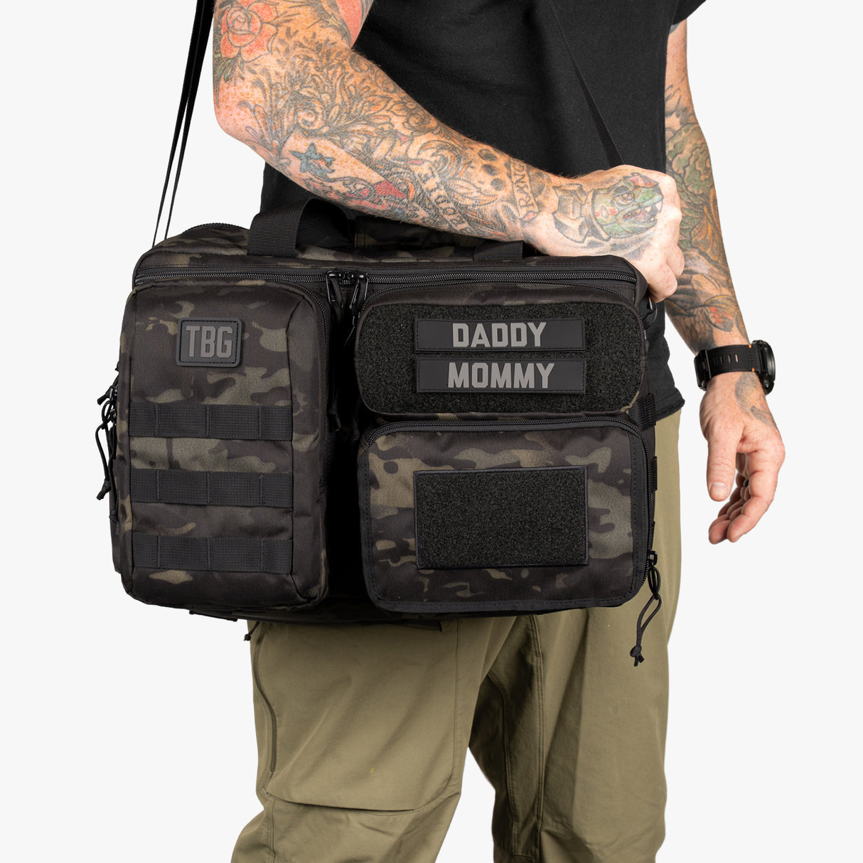 Rugged Deuce Diaper Bag in camo with adjustable strap, featuring customizable patches for parents.