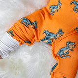 Infant wearing orange zippie pajamas with playful dinosaur prints, perfect for cozy and fun sleepwear.