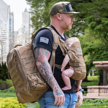 man standing in a park with tactical baby carrier and diaper bag backpack