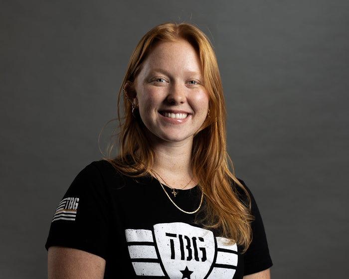 Woman in black and white military-style T-shirt with bold "TBG" logo.