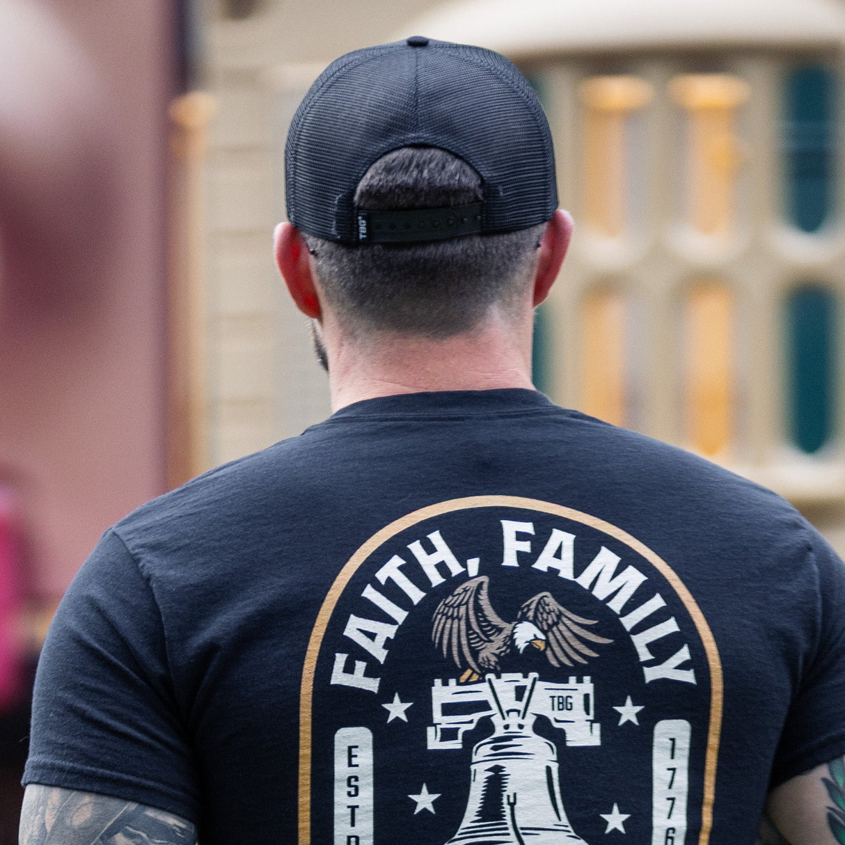 Man wearing a black t-shirt with 'Faith, Family, Freedom' design in an outdoor setting.