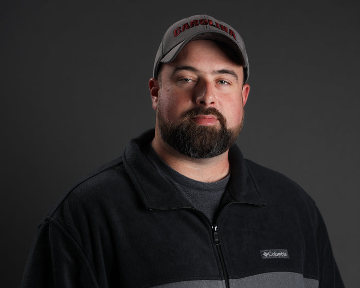 Man in a black Columbia fleece jacket and gray tactical cap.
