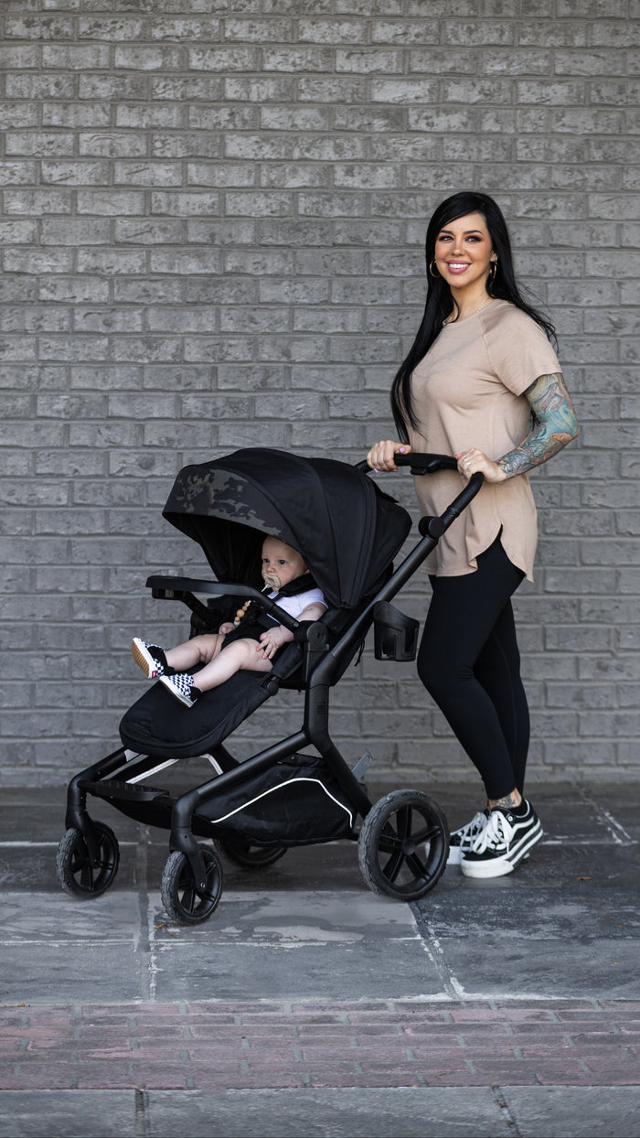 happy mom standing with tactical baby gear stroller