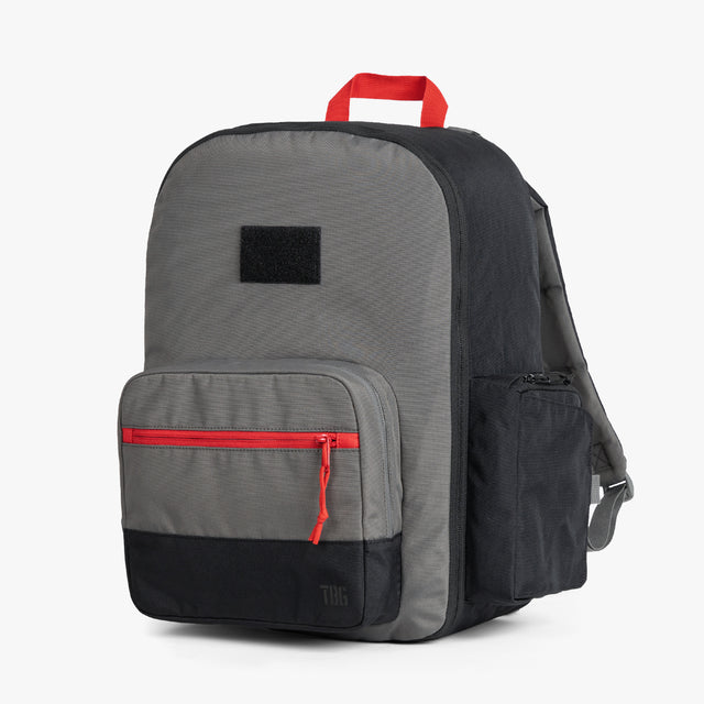 Gray classic diaper backpack with red accents and multiple compartments, featuring a main zip section, front pocket with a red zipper, and side bottle pockets., Men's Diaper Bag