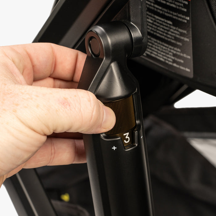 Person adjusting the shock suspension system on a TBG Veer Switchback double stroller.