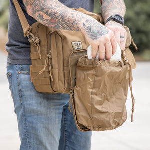 Man placing diaper into dump pouch that is open and affixed to diaper bag. 