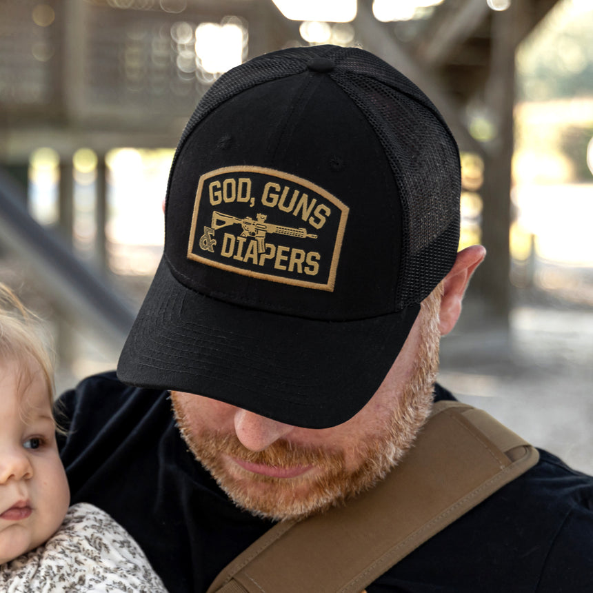 Man wearing black God, Guns & Diapers hat