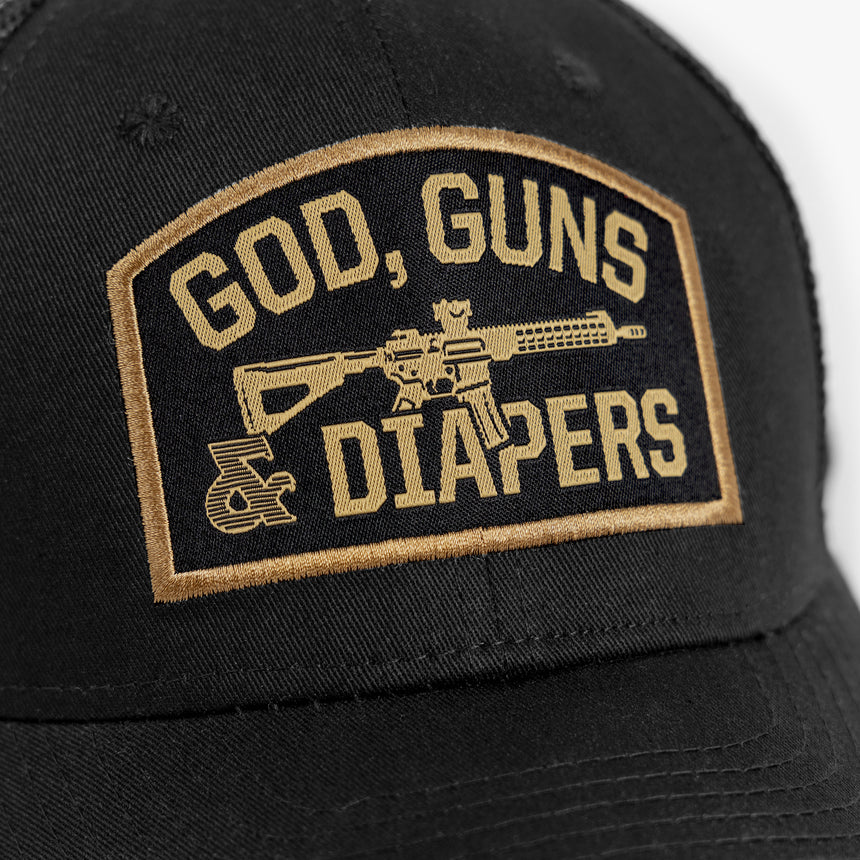 Close up of gold embroidery reading God, Guns & Diapers on black background