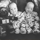 Black and white picture of twin infants cuddling with Tactical Teddy®f