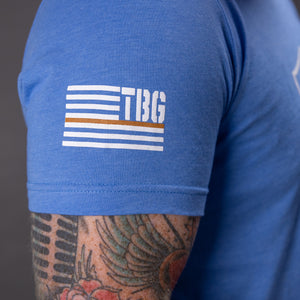 T-shirt sleeve with TBG branded flag featuring thin brown line. 