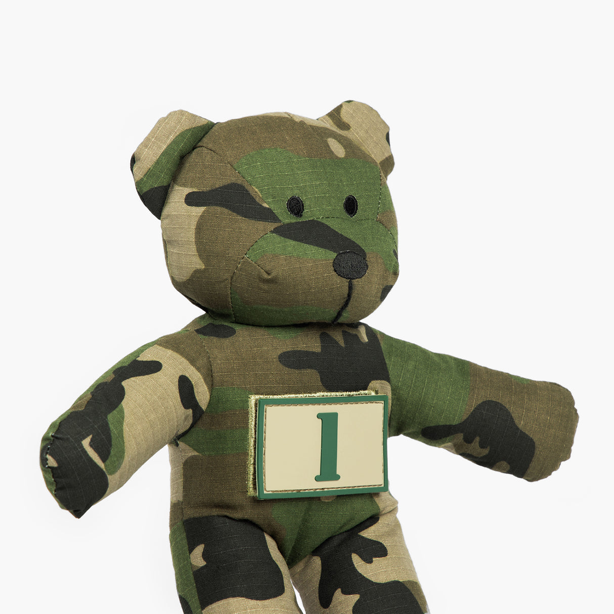 Camouflage teddy bear wearing tan patch with a green number 1 on it. 