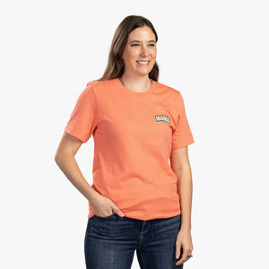 Front view of woman wearing coral t-shirt with small mama on top left.
